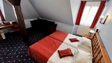 Un dormitorio con cama, mesita de noche, lámpara y ventana con cortinas.