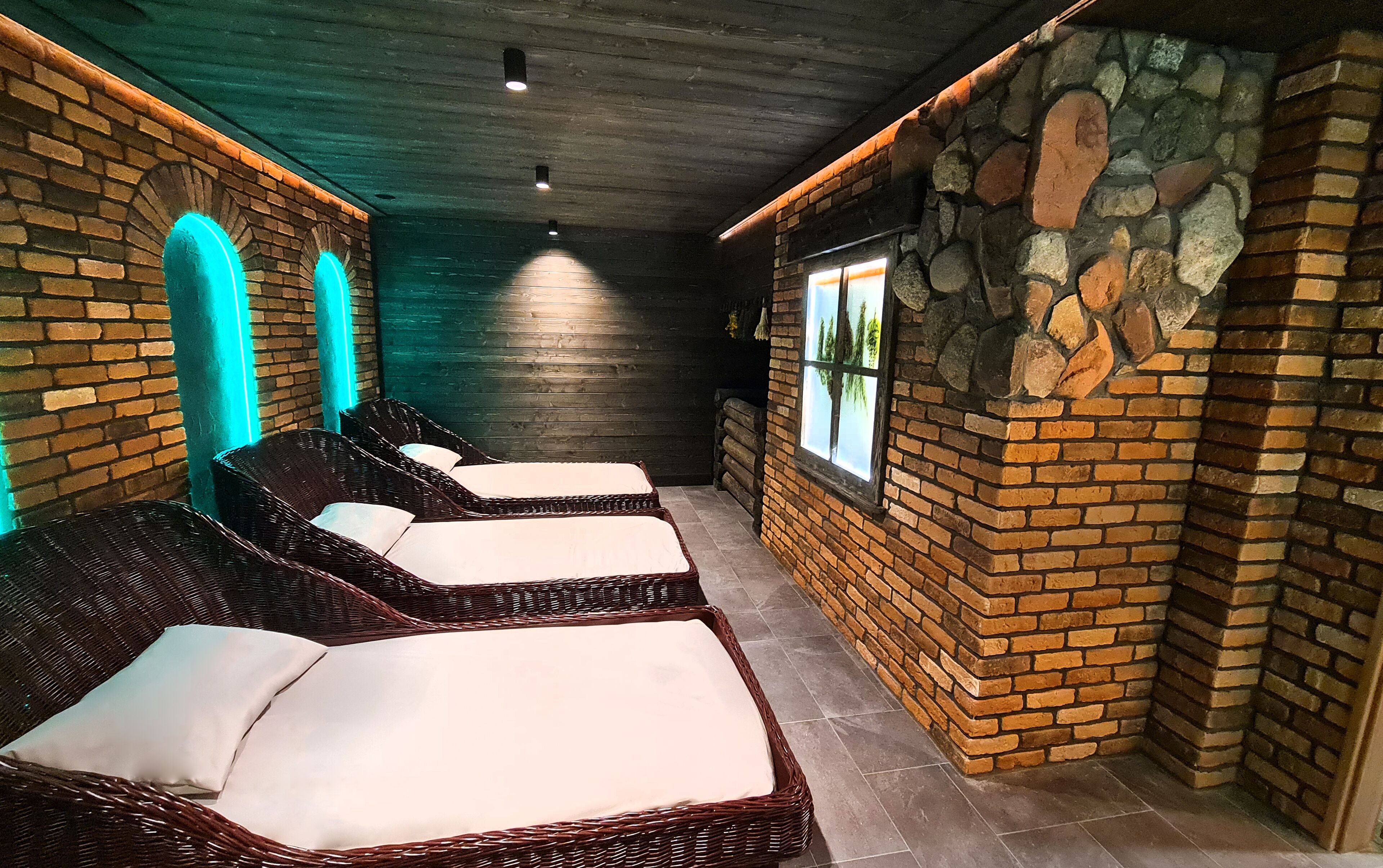 Un cuarto de spa con sillones de mimbre, una pared de piedra y un ventanal con vistas.