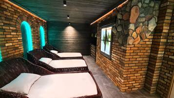 Un cuarto de spa con sillones de mimbre, una pared de piedra y un ventanal con vistas.