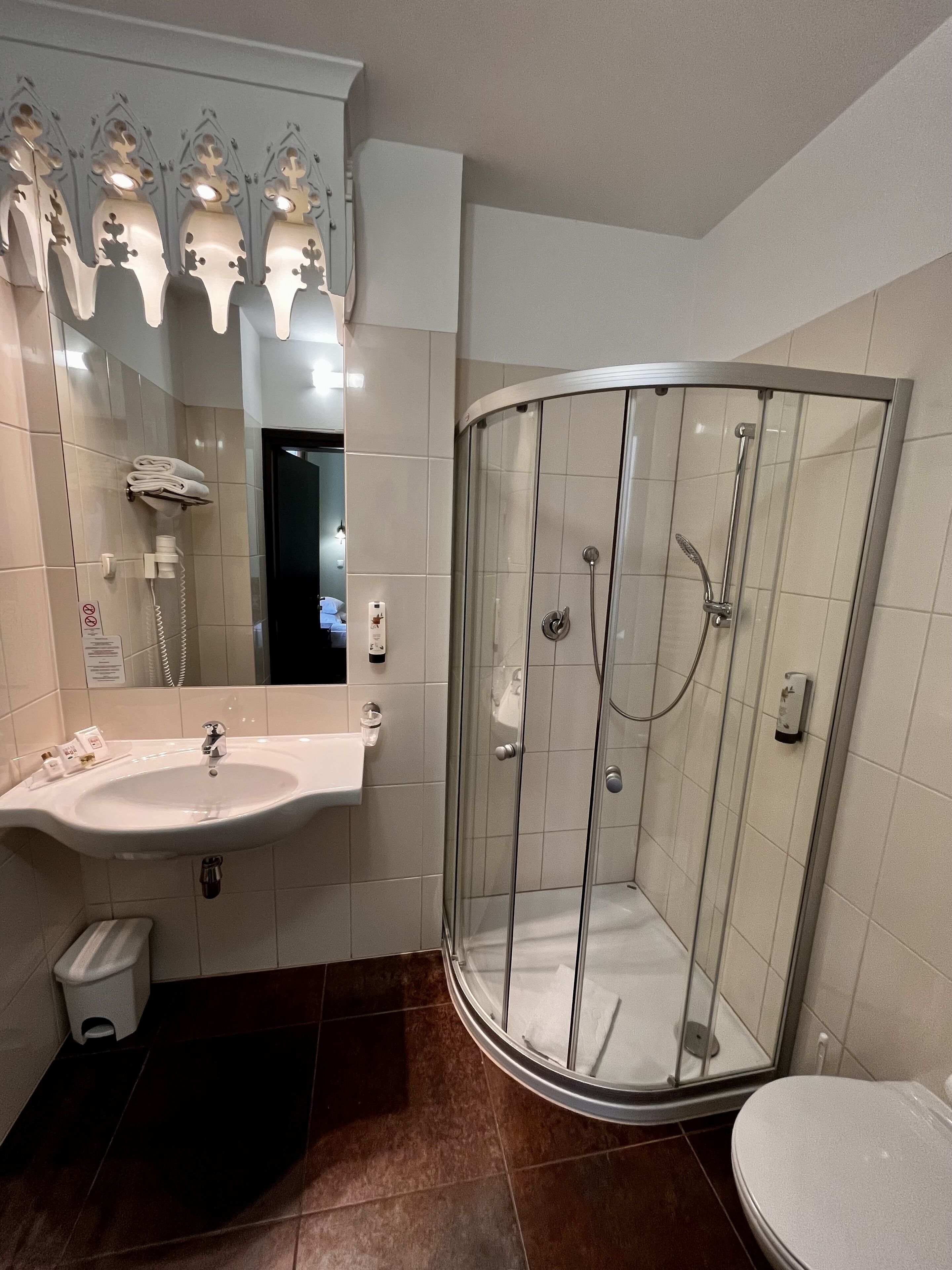 Un baño moderno con ducha de vidrio, lavabo con espejo e inodoro.