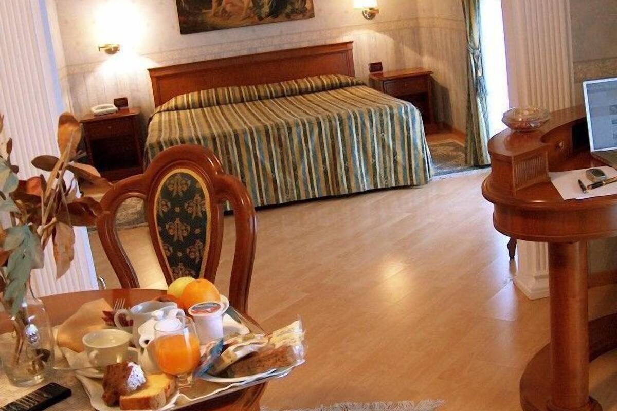 Une chambre d’hôtel équipée d’un lit, d’un bureau et d’un plateau de petit-déjeuner avec de la nourriture et des boissons.