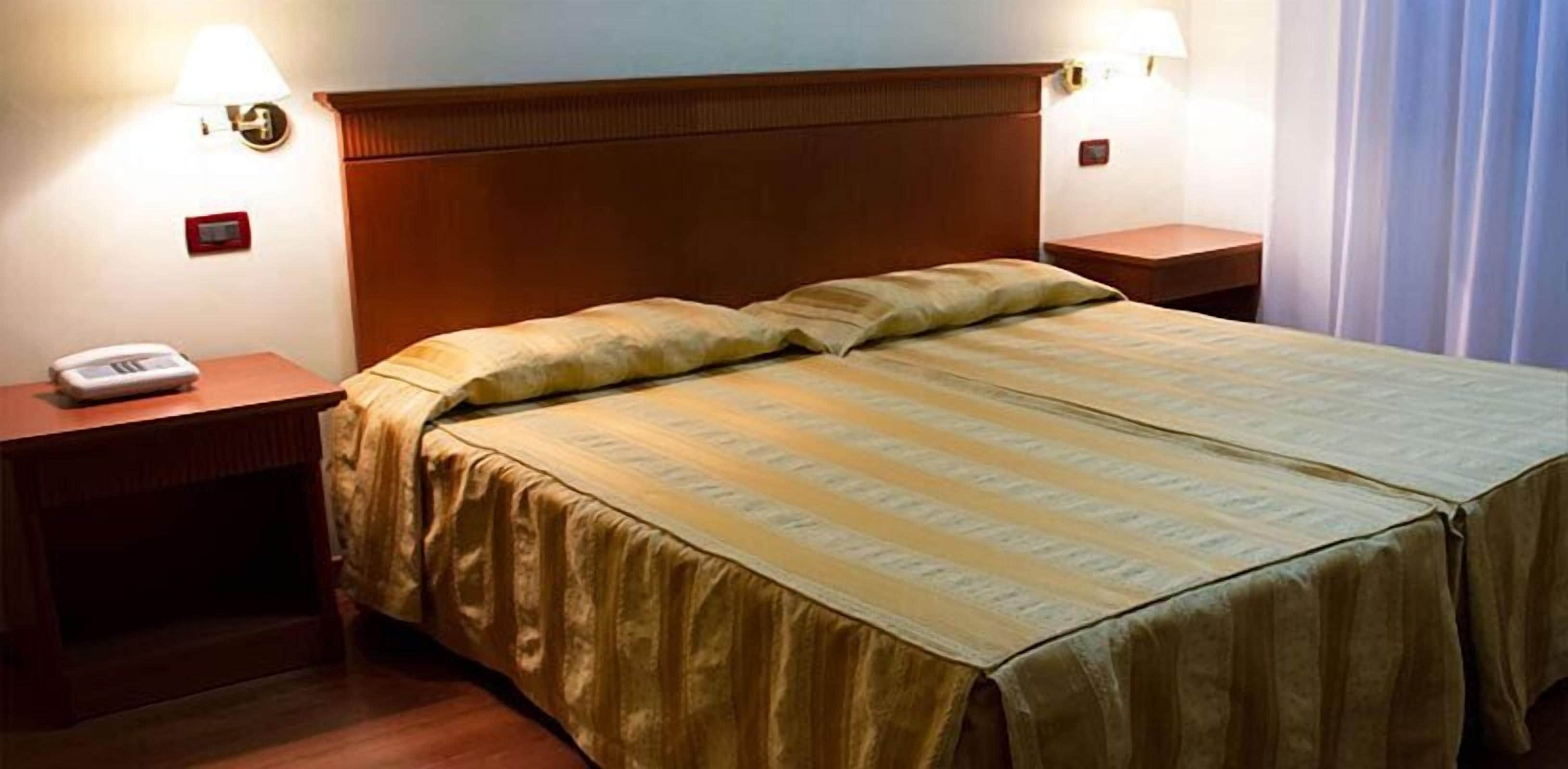 Ett hotellrum med en dubbelsäng, två sängbord, en lampa och en telefon på ett av borden.