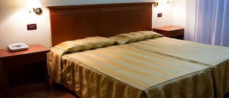 A hotel room with a double bed, two bedside tables, a lamp, and a phone on one table.
