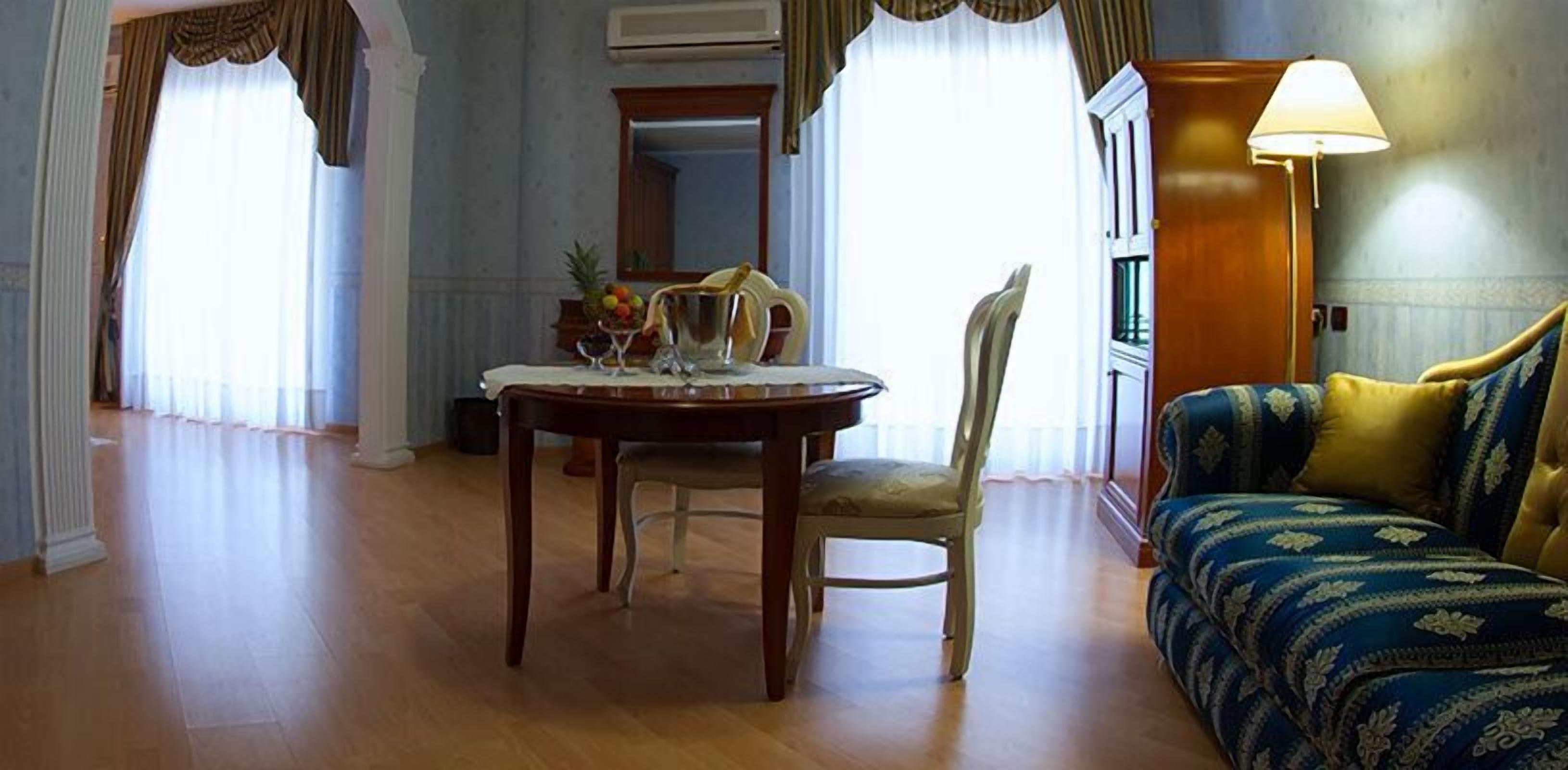 Habitación de hotel con una mesa de comedor, una silla, un sofá y una lámpara.