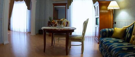 Habitación de hotel con una mesa de comedor, una silla, un sofá y una lámpara.
