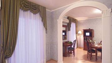 A room with a dining area, a television, and a large window with curtains.