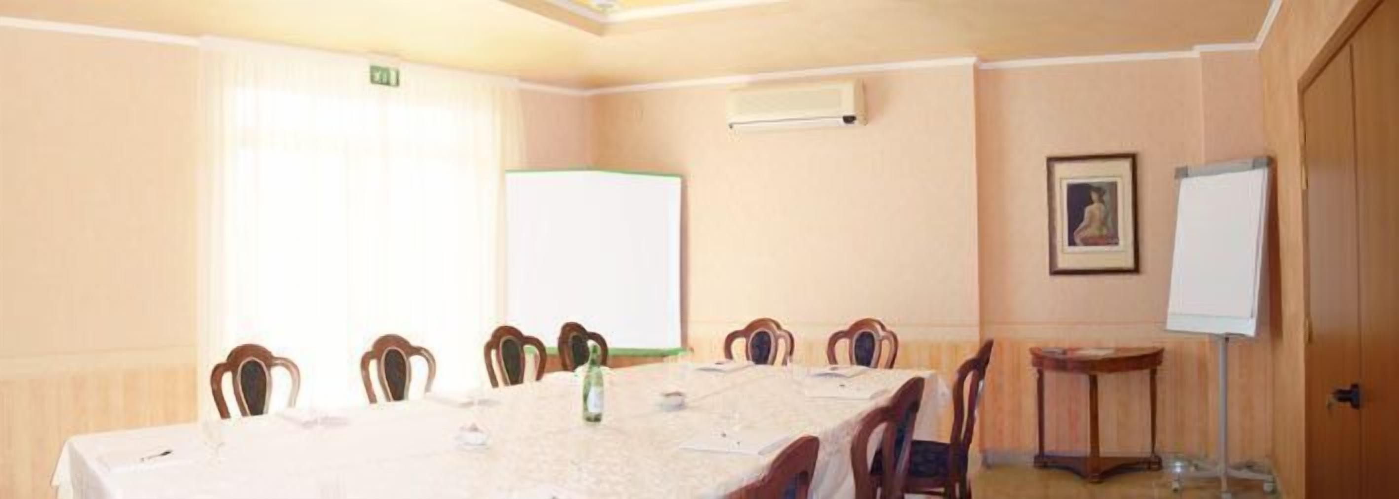 Una sala de conferencias con una larga mesa, sillas, una pizarra y un cuadro en la pared.
