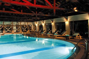 Una piscina cubierta, una piscina al aire libre, sombrillas, tumbonas