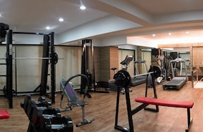 A gym with various exercise equipment, including a bench, weight machines, and cardio machines.