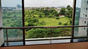 A room with a large window offering a view of a green landscape and distant buildings.