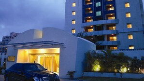 A modern hotel with a curved facade, a car parked in front, and a well-lit entrance.