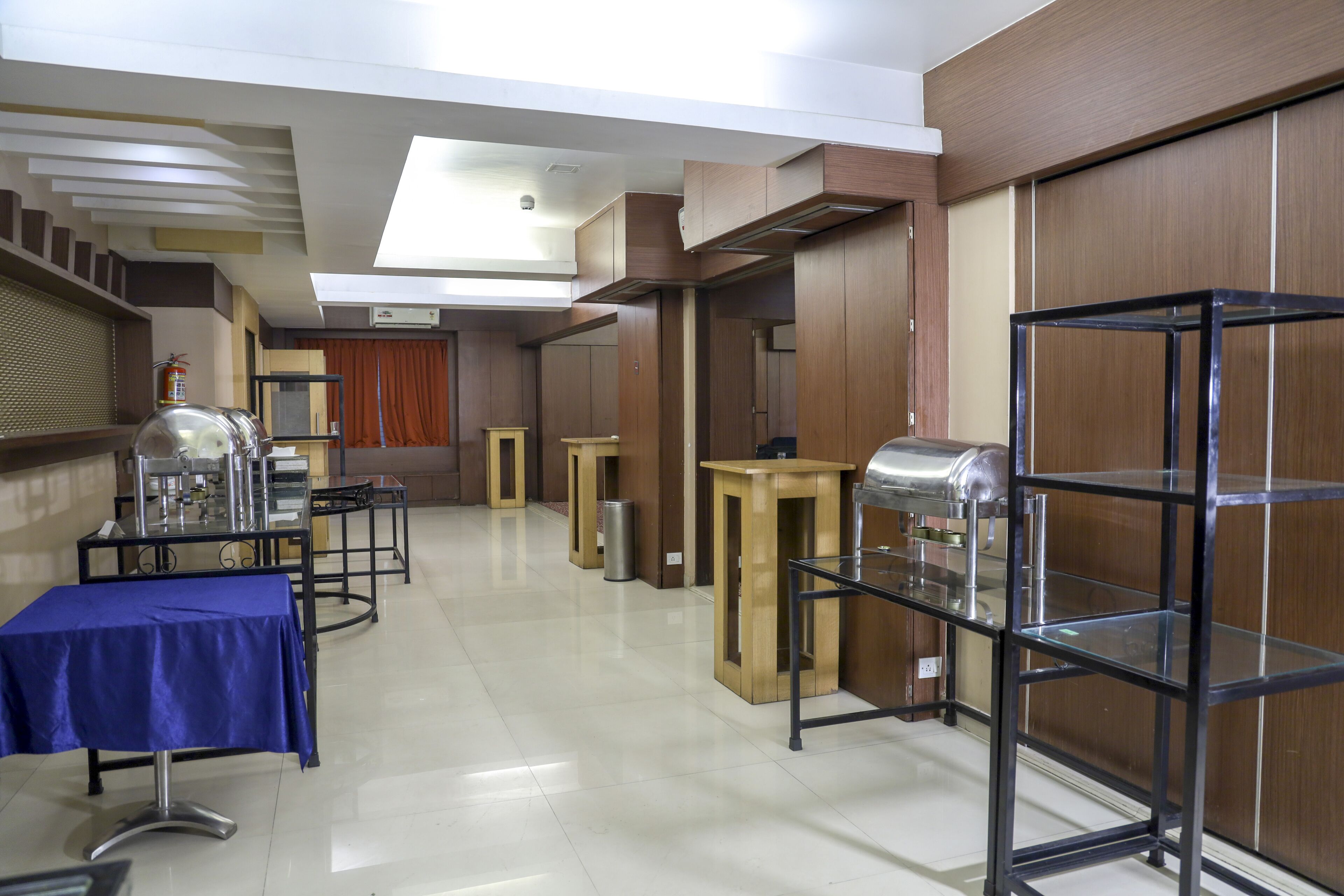 A hotel room with a blue table, a glass display case, and a wooden cabinet.