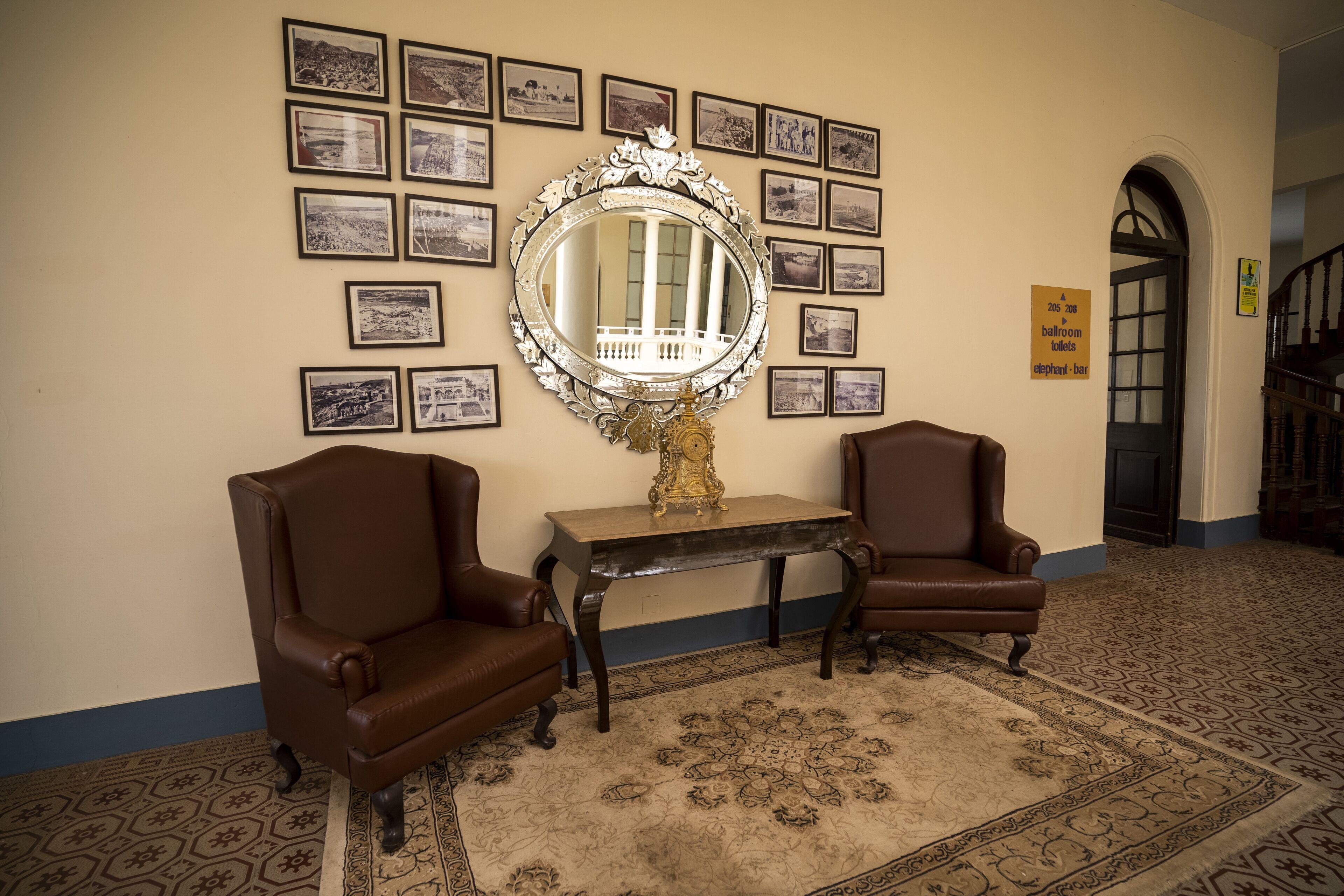 A room with two brown leather armchairs, a large ornate mirror, and a patterned carpet.
