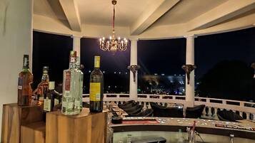Eine Bar mit Flaschen und Gläsern, einer Kronleuchter und Blick auf eine nächtliche Skyline.