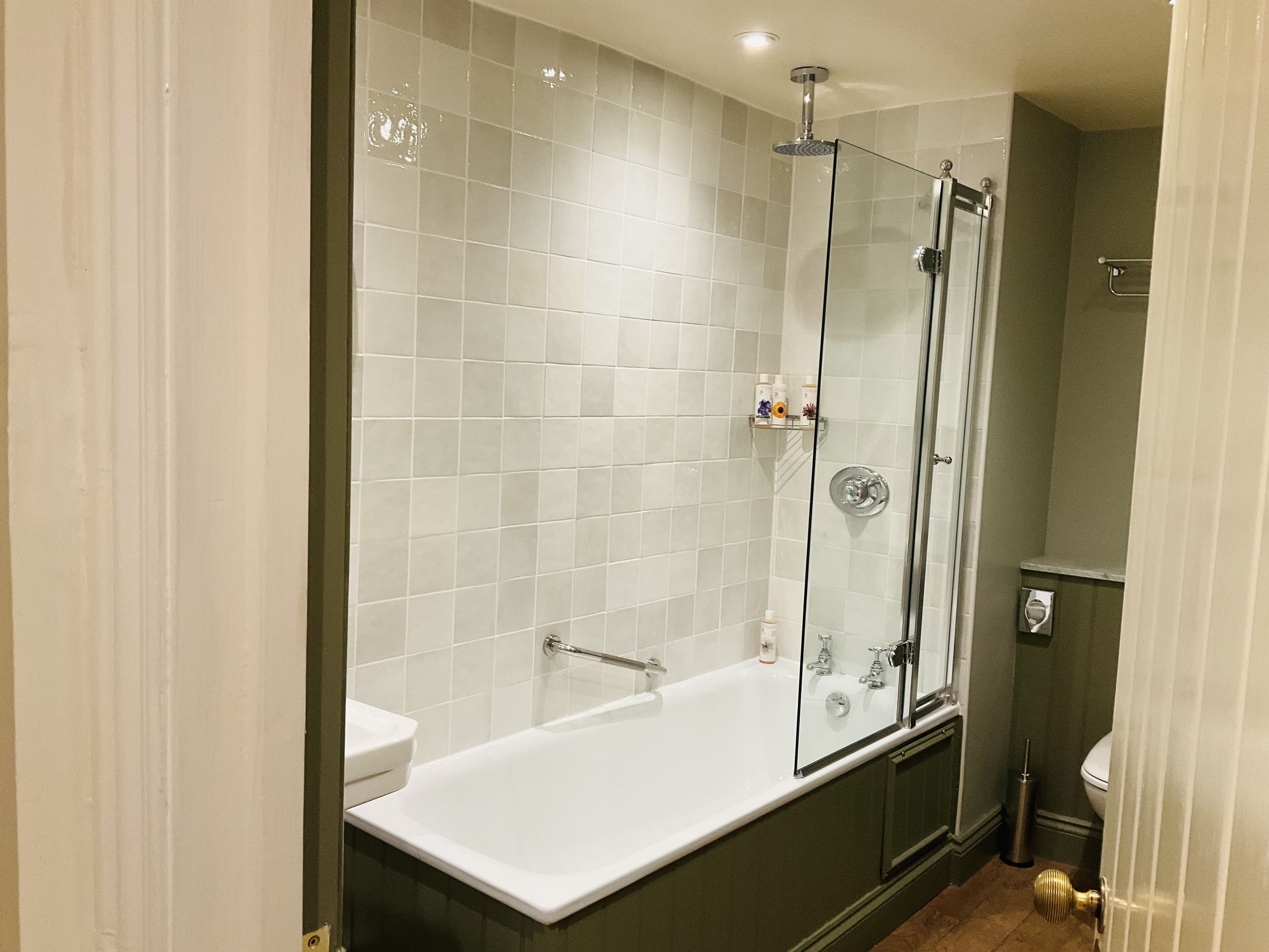 Un baño moderno con ducha envuelta en vidrio, una bañera blanca y un inodoro.