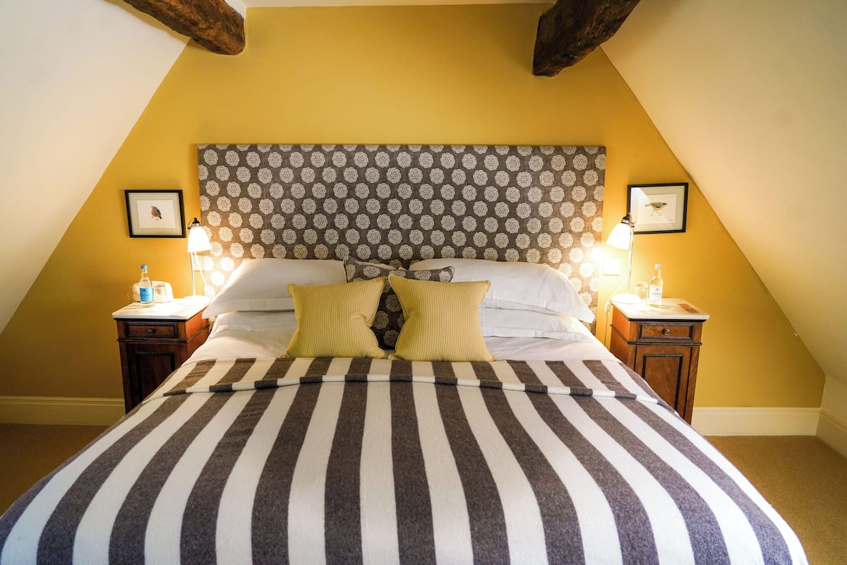 A bed with striped bedding, a patterned headboard, and two bedside lamps.