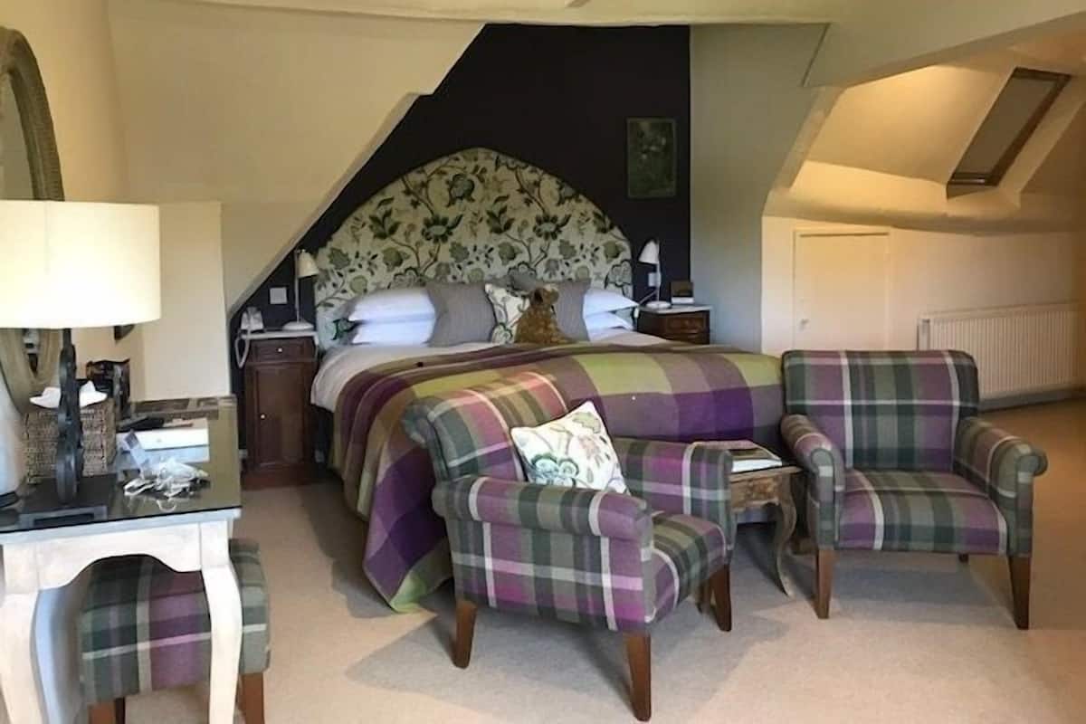 A bedroom with a bed, two chairs, a desk, and a lamp.