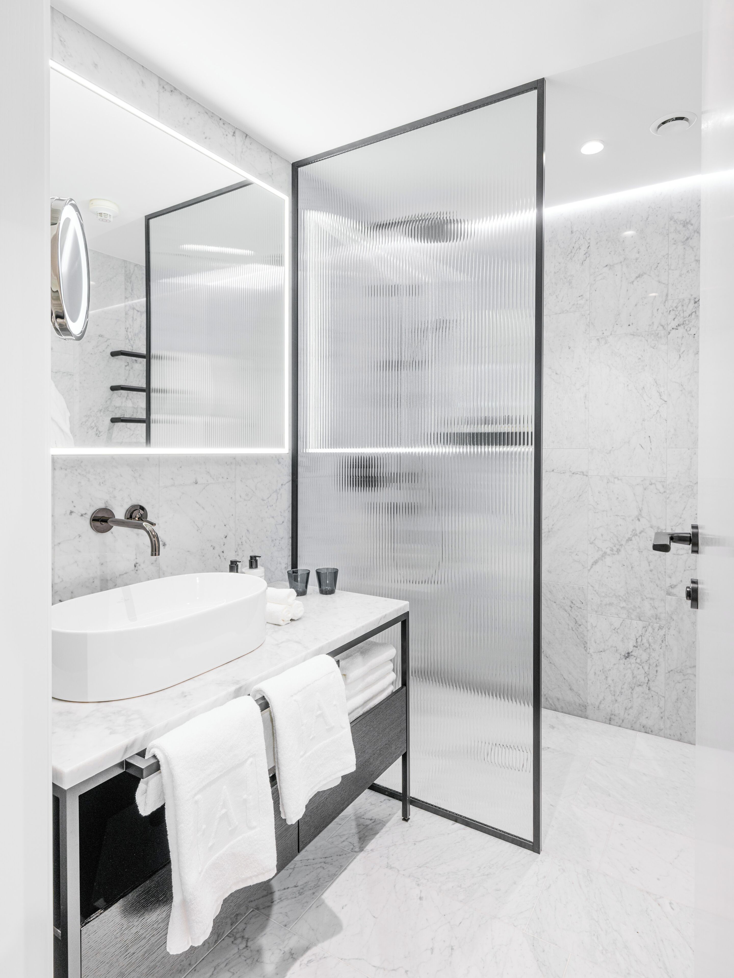 Un baño moderno con un lavamanos grande, espejo y cabina de ducha.