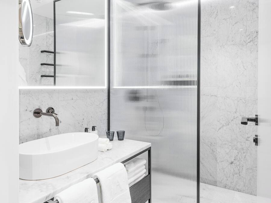 Un baño moderno con un lavamanos grande, espejo y cabina de ducha.