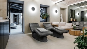 Een moderne spa-ruimte met twee fauteuils, een bank en een houten bijzettafeltje.
