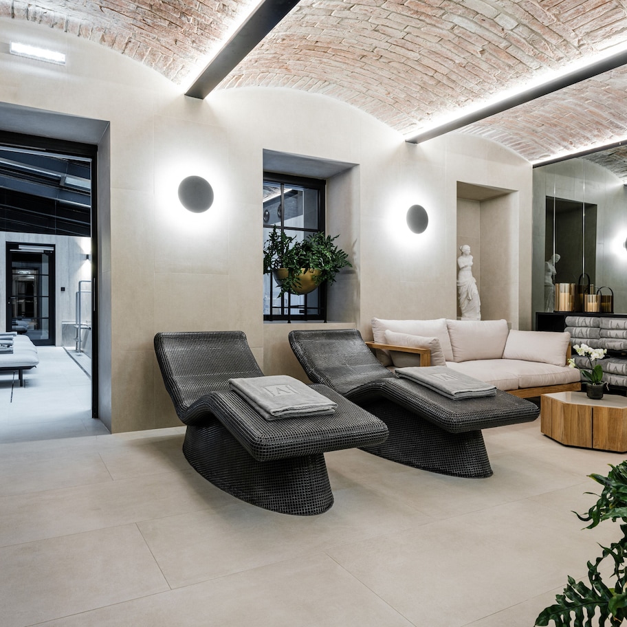 A modern spa area with two lounge chairs, a sofa, and a wooden side table.