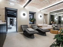 A modern spa area with two lounge chairs, a sofa, and a wooden side table.