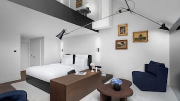 Un dormitorio moderno con una cama grande, un escritorio, una silla y una mesita con un florero.