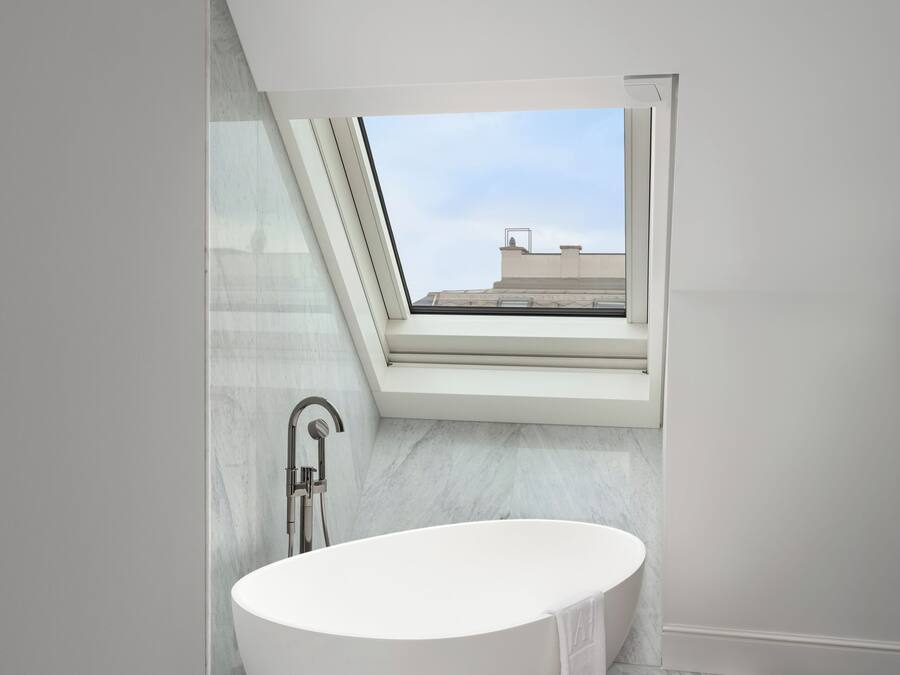 Un baño moderno con una bañera independiente, un tragaluz y vistas a la ciudad.