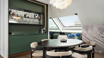 A modern dining area with a round table, six chairs, a bar area with shelves, and a skylight.