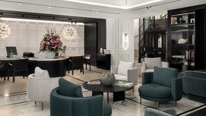 Een moderne, goed verlichte lobby met een receptiebalie, zithoek en een boekenkast.