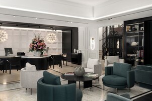 A modern, well-lit lobby with a reception desk, seating area, and a bookshelf.