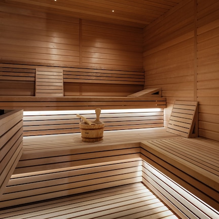 A sauna with wooden benches and a wooden bucket with a brush.