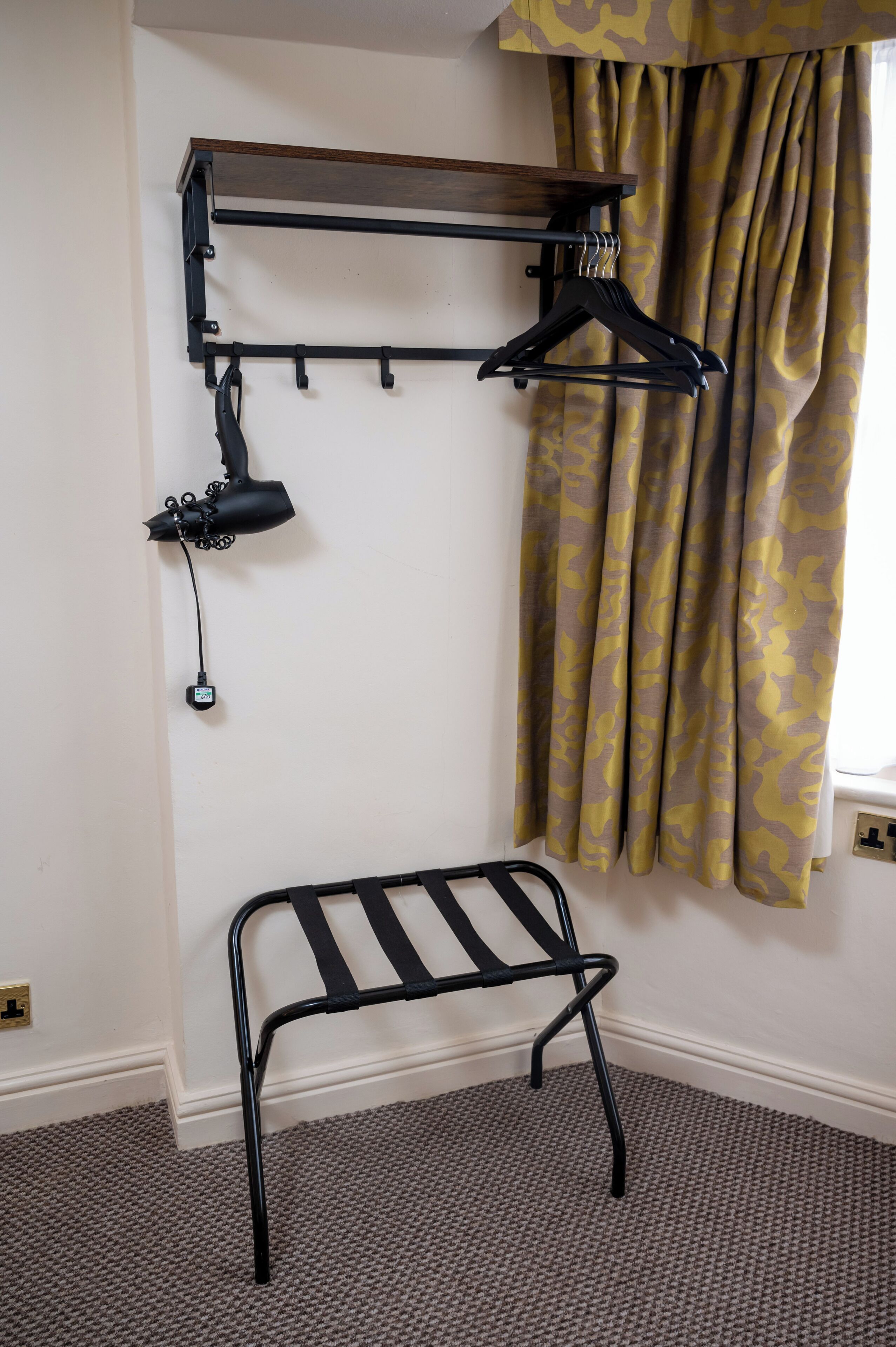 A room with a black metal bench, a wall-mounted drying rack, and a lamp.