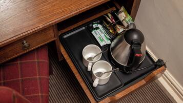 A drawer with a tray containing two white mugs, a black electric kettle, and some milk cartons.