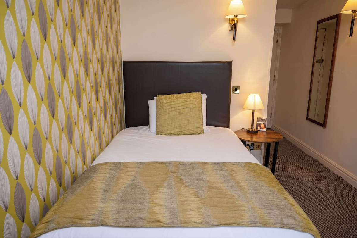 Une chambre d’hôtel avec un lit, une table de chevet, une lampe et un miroir.