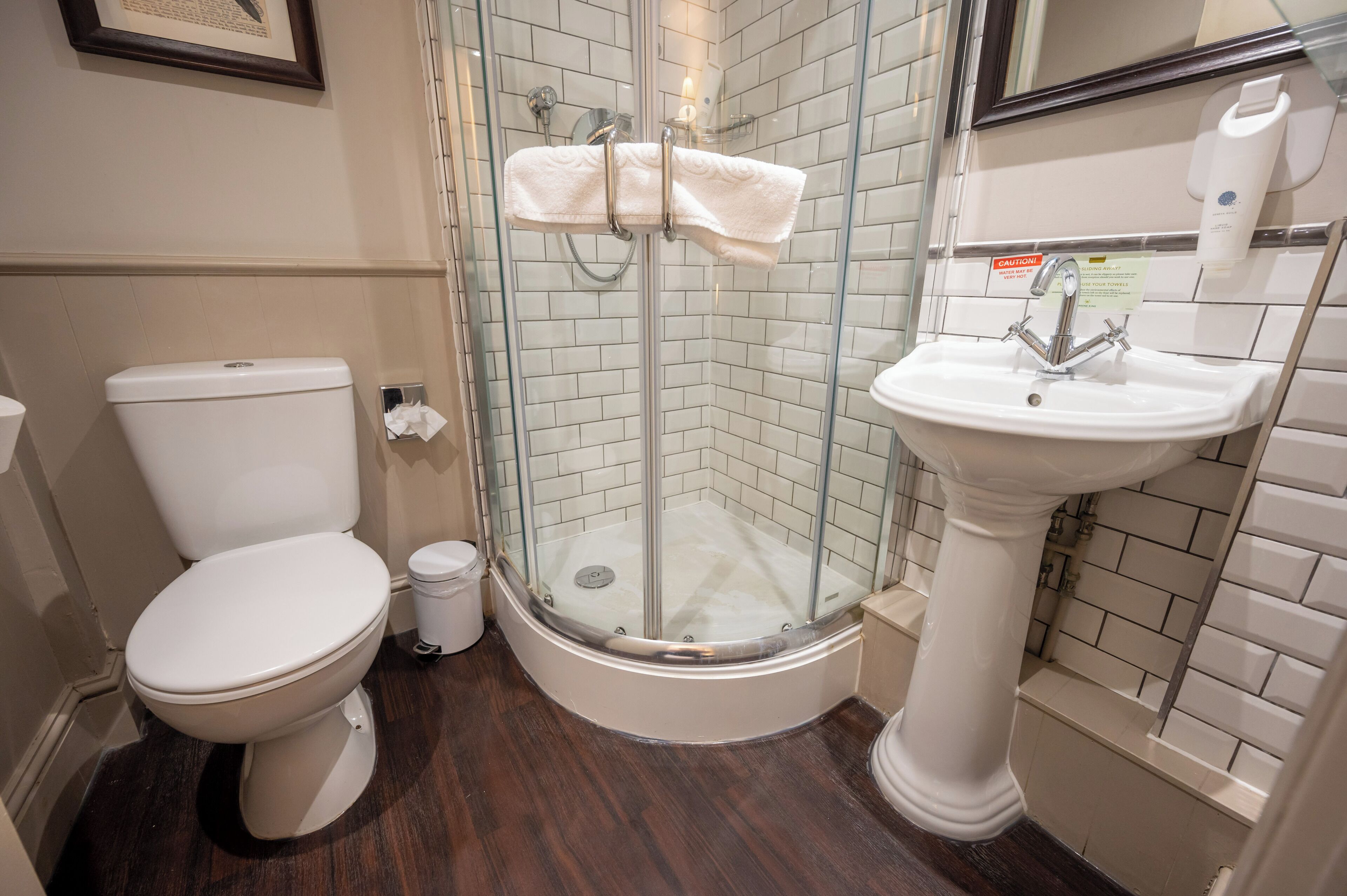 A bathroom with a toilet, a glass-enclosed shower, and a sink.