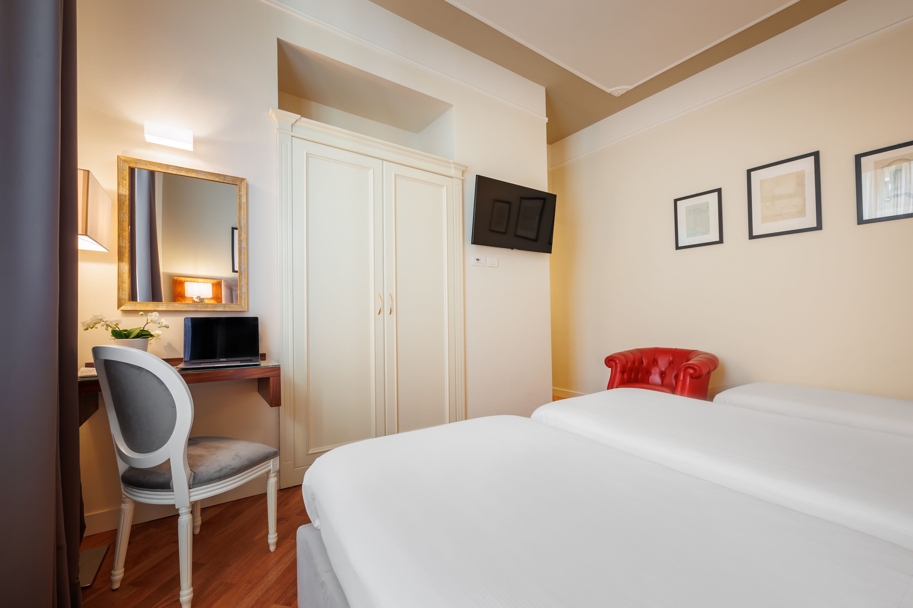 Una camera d'albergo con un letto, una scrivania con sedia, una TV a parete e un armadio.