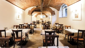 Un restaurant amb sostre de maó, parets blanques i diverses taules i cadires.