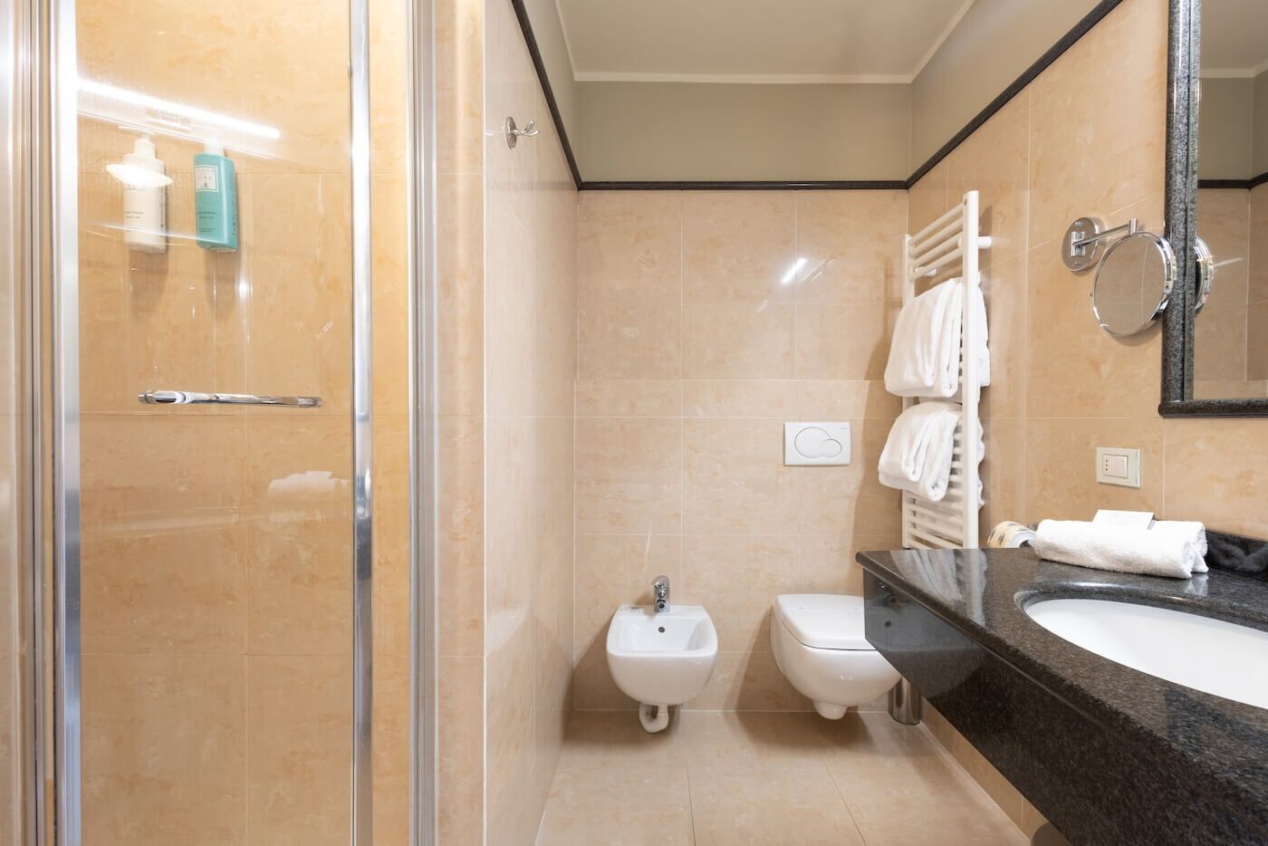 Un bagno moderno con cabina doccia in vetro, lavandino a piedistallo e mobile vanità con specchio.