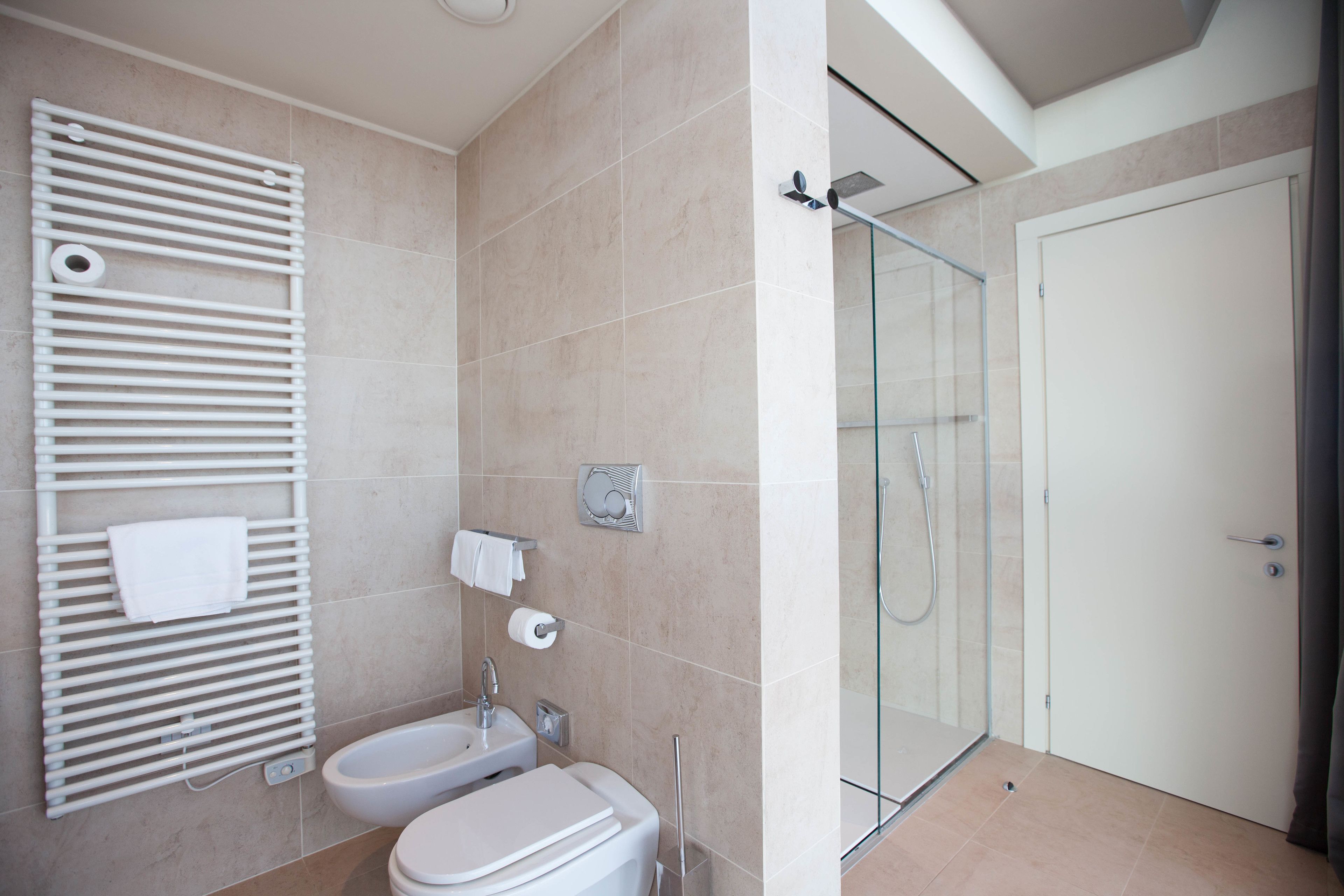 A modern bathroom with a glass shower enclosure, a white sink, and a towel rack.