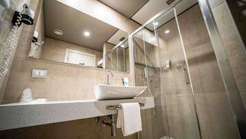 A modern bathroom with a large mirror, a sink, and a glass shower enclosure.