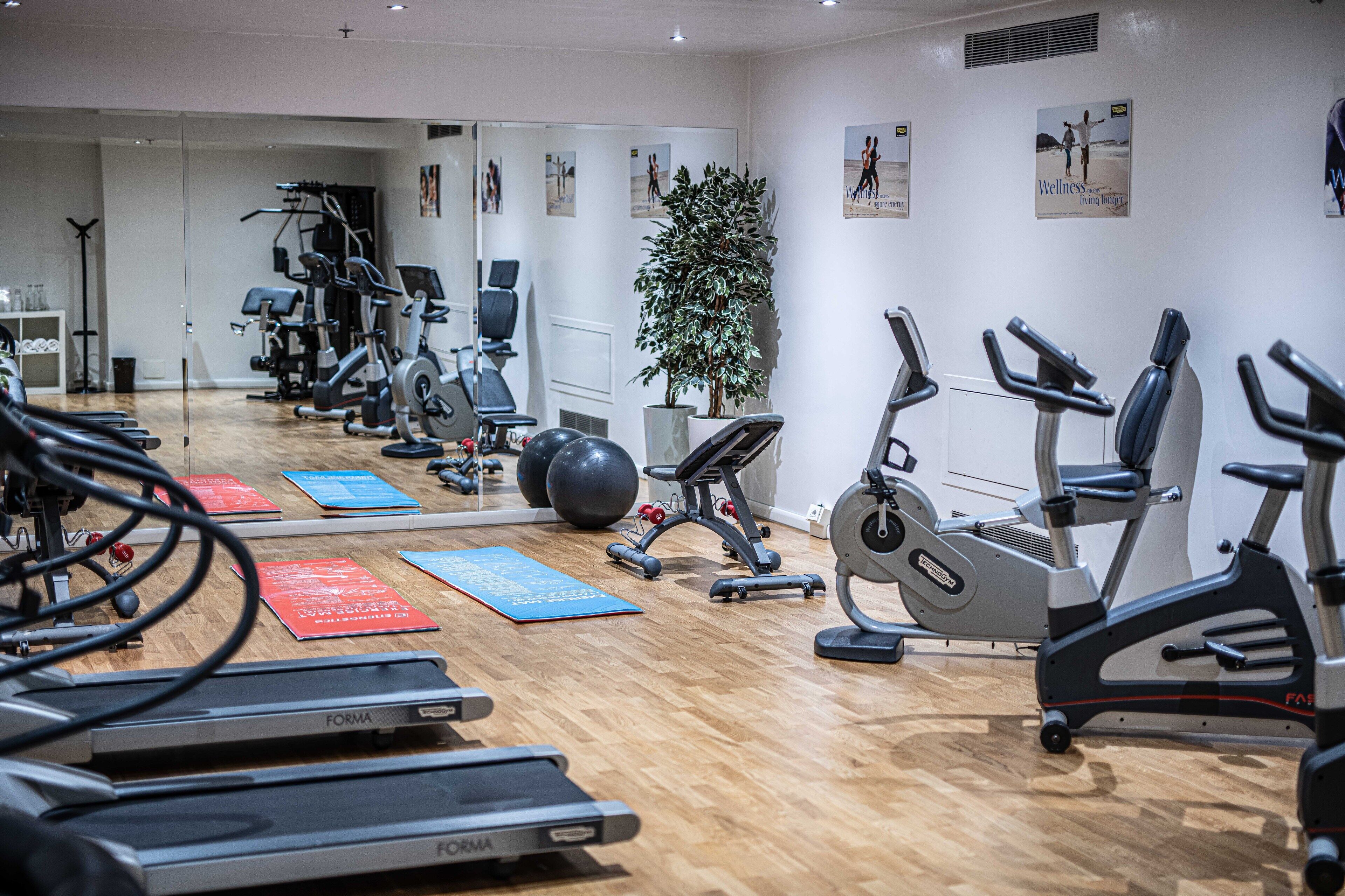 A gym with treadmills, stationary bikes, and exercise balls.