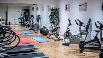 A gym with treadmills, stationary bikes, and exercise balls.