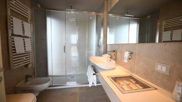 Un baño moderno con cabina de ducha de vidrio, un lavabo blanco y un bidé.