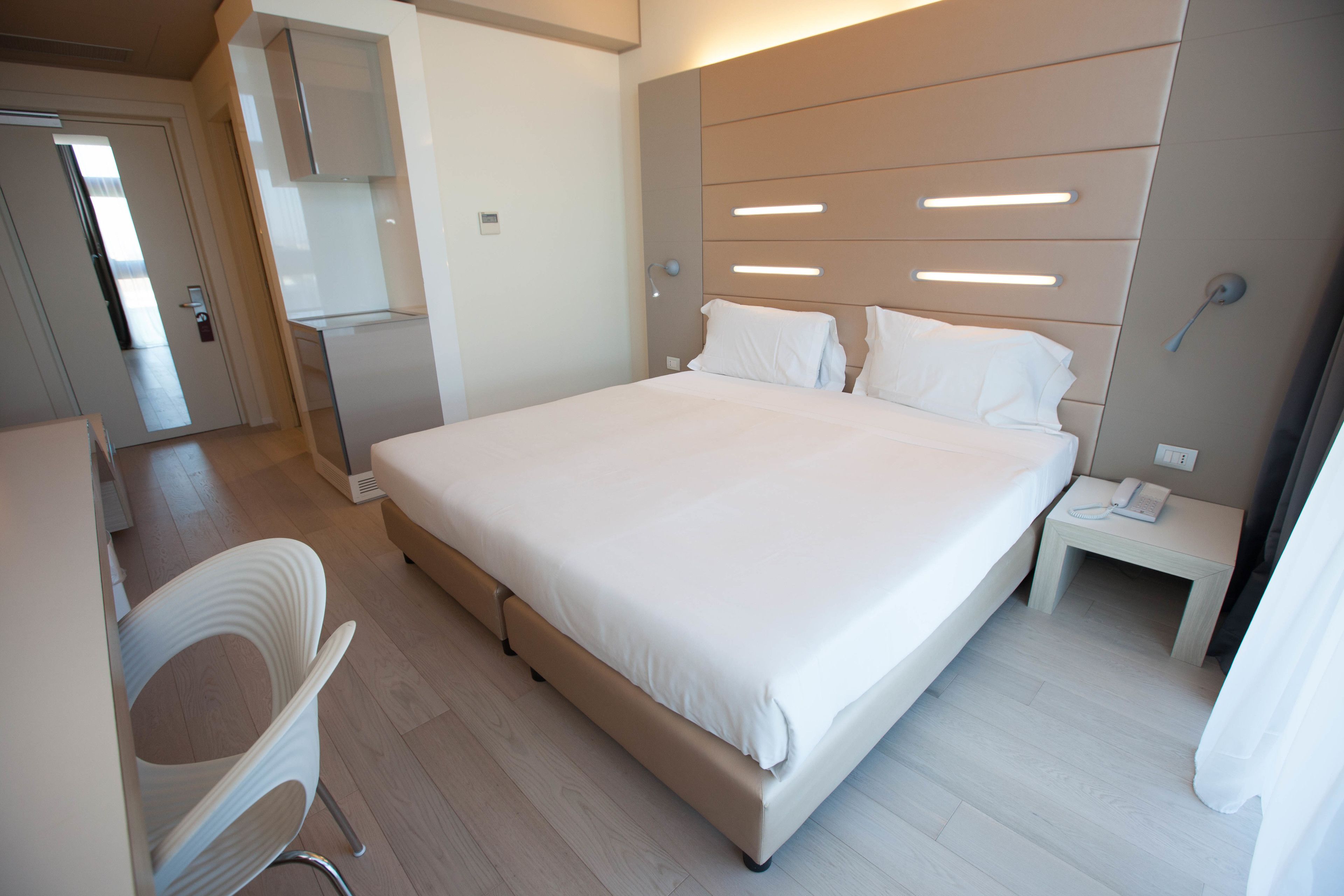 Una habitación de hotel moderna con una cama grande, un escritorio y una silla.