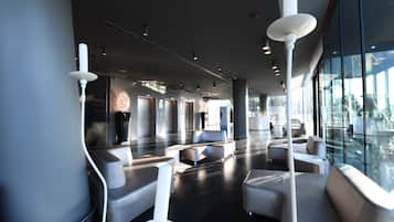 Eine moderne Lobby mit großzügiger Sitzecke, großen Fenstern und zeitgemäßen Leuchten.