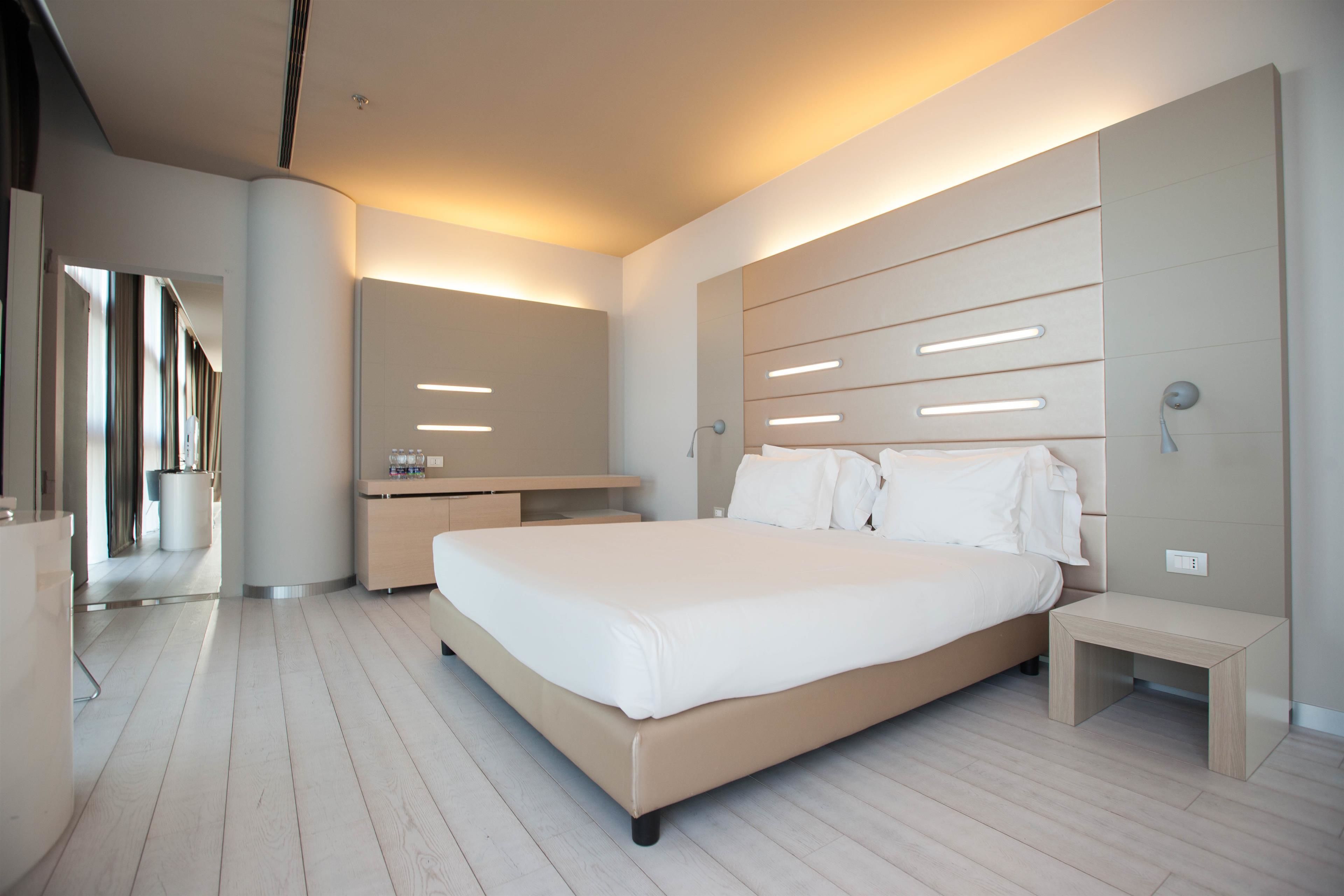 A modern bedroom with a large bed, bedside tables, and built-in lighting.