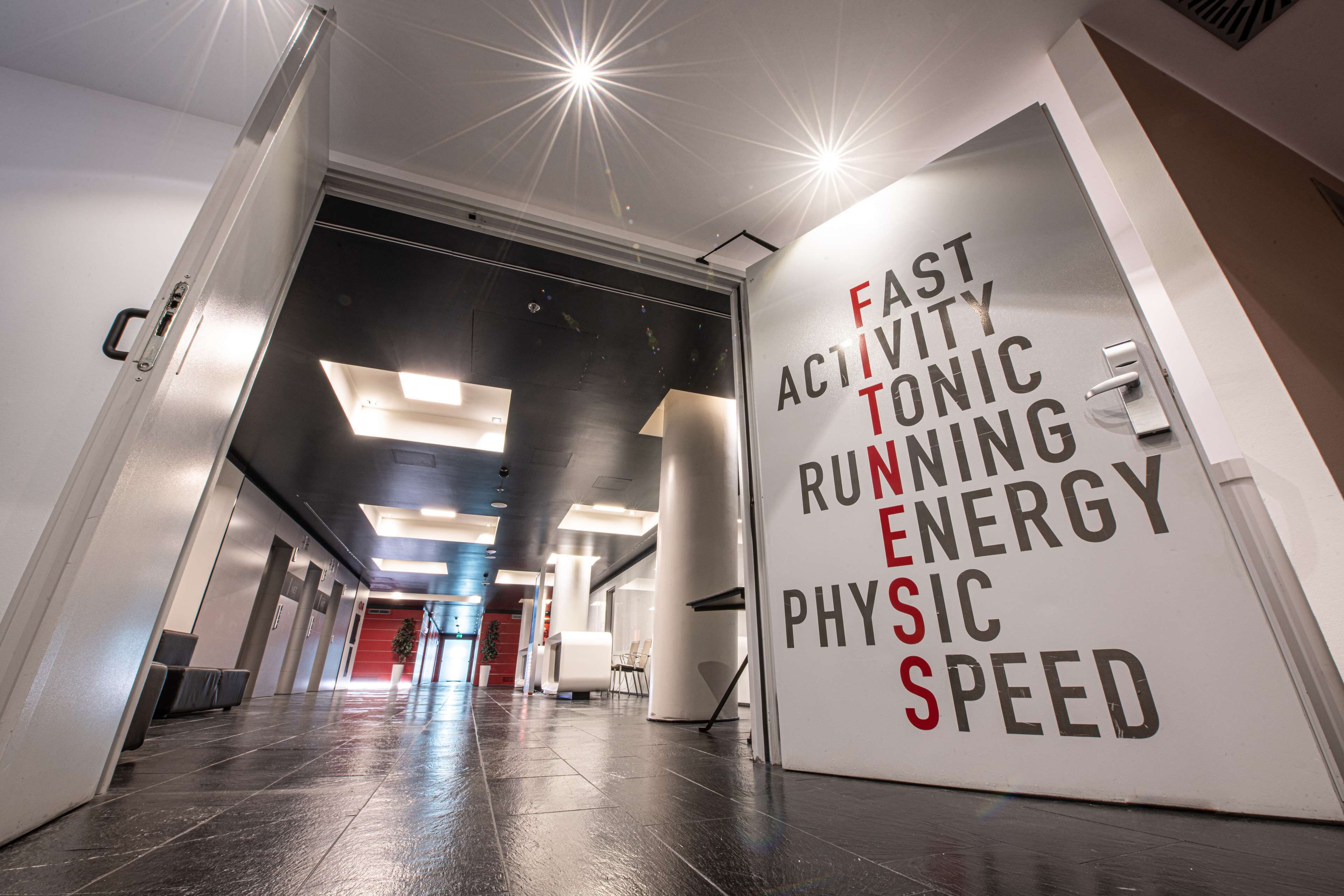A hallway with a sign reading "FAST ACTIVITY RUNNING ENERGY PHYSICAL SPEED".
