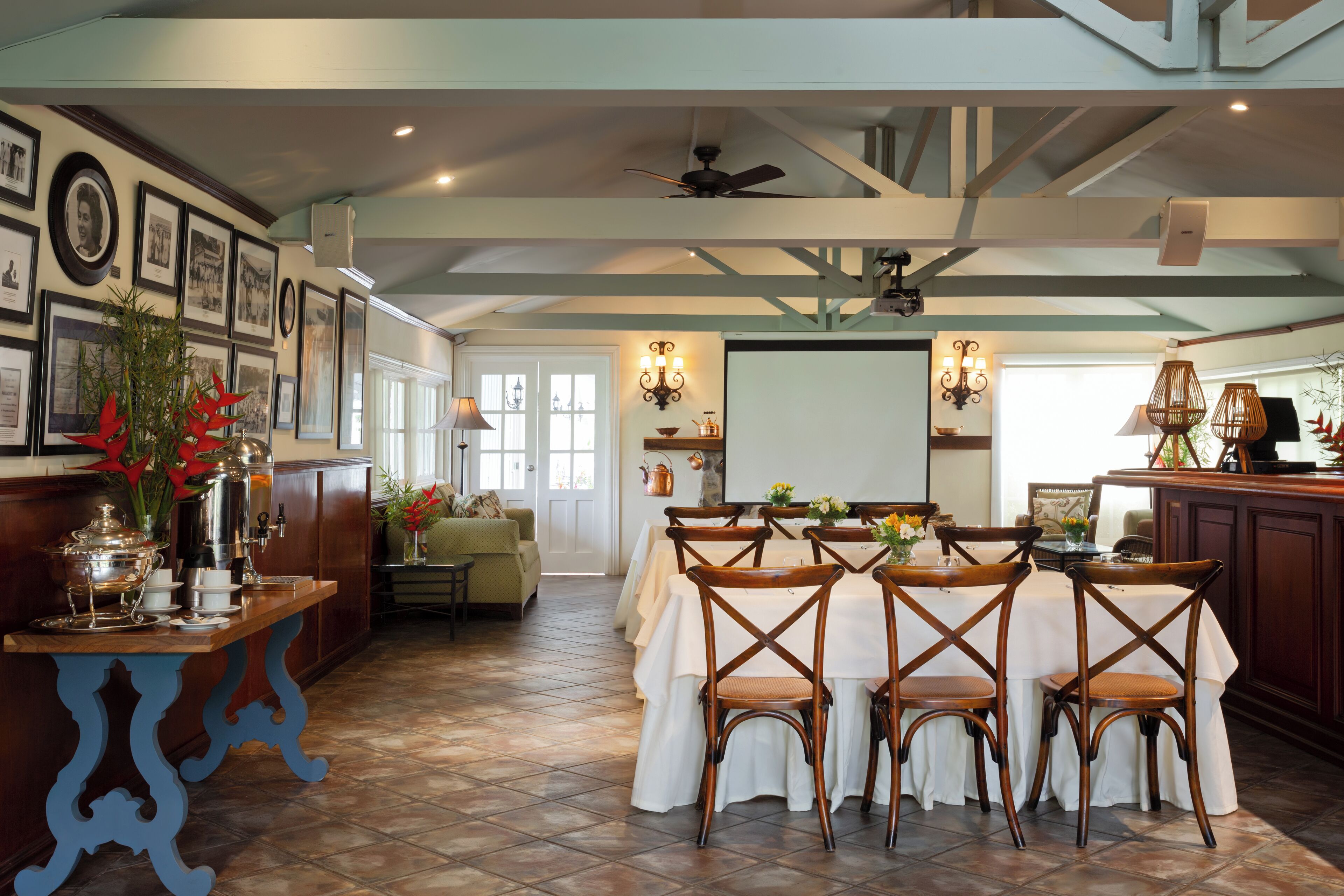 A dining area with a table set for four, surrounded by wooden chairs, a ceiling fan, and wall-mounted lighting.