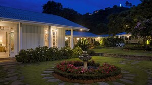 Un edificio ben illuminato con giardino, vialetto in pietra e una fontana.